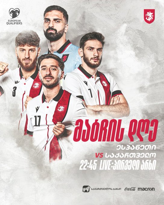 Four Georgian national football players stand in a group pose on a misty gray background. They wear red and white uniforms with number 3 on one, number 11 on another, and sponsor logos like Macron. Georgian text reads Asori Omi vs. Spain on 22-24 LIVE. UEFA qualifiers logo appears at top left with Spanish and Georgian flags. Georgian coat of arms emblem is at top right. Coca Cola and Macron sponsor logos are at bottom.