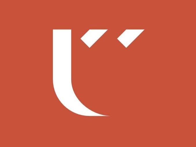 A stylized white logo on a solid red background. The logo features a large, curved letter "U" with two small chevron-like marks above it, resembling quotation marks.