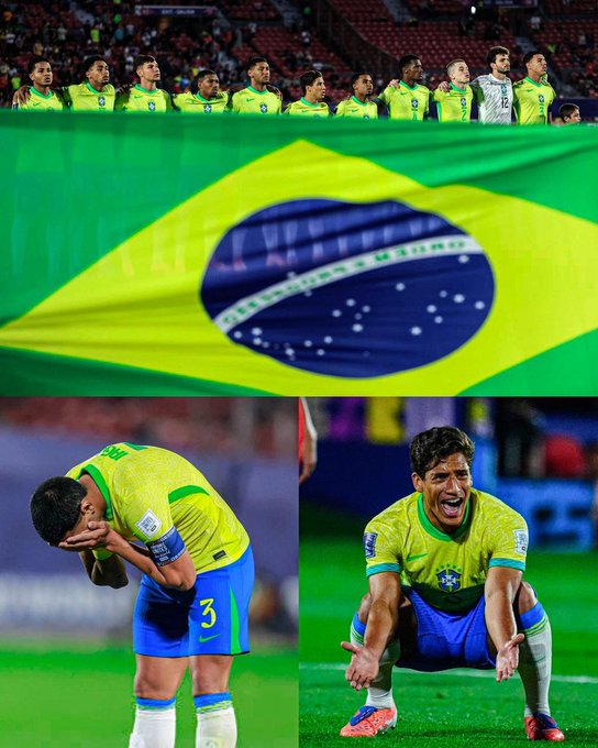 A large Brazilian flag with a blue globe and stars. A group of soccer players in yellow and green jerseys with blue shorts, standing in a line on a field. One player in a yellow and green jersey with the number 3 on the back, head bowed. Another player in a yellow and green jersey, crouching on the field with arms outstretched.