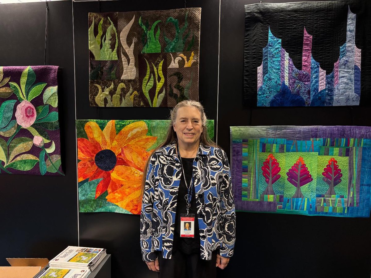 Our own staff member Ann Graf in the Show Office with quilts that she made!