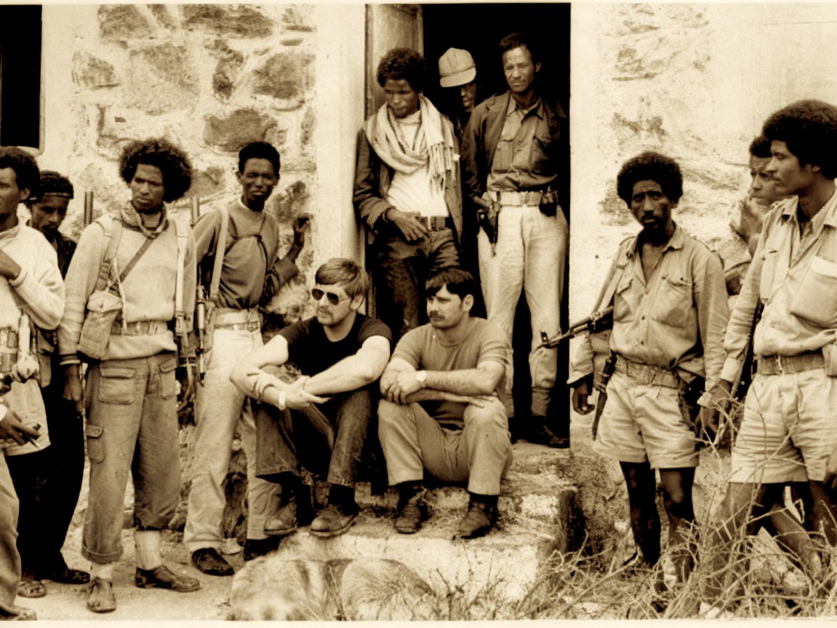 ytmn2's tweet photo. In this picture, you see two American servicemen stationed at Kagnew Station who were kidnapped by Eritrean freedom fighters in 1975: Tom Bowidowicz (left) and David Strickland (right). The Eritrean fighters allowed them to meet with Gwynne Roberts, a journalist from the Financial Times. Following the interview and the photo session, the freedom fighters released them, having explained the reasons behind the long struggle for freedom. Kagnew Station was a United States Army installation located in Asmara, Eritrea, on the Horn of Africa. Established in 1943, it functioned as a U.S. Army radio station, taking over and refurbishing a pre-existing Italian naval radio facility after Italian forces in Asmara surrendered to the Allies in 1941. Kagnew Station operated until April 29, 1977, when the last Americans departed. It housed the United States Army’s 4th Detachment of the Second Signal Service Battalion. As a Cold War listening station, Kagnew Station was situated near the equator at an altitude of 7,300 feet (2,200 meters) above sea level. Kagnew Station became home to over 5,000 American citizens at its peak in the 1960s. The closure of the Ethiopian military’s Keren R&R Center, located in the city of Keren, occurred in 1971 due to fighting between the Ethiopian military and Eritrean resistance fighters. Shortly after, the Massawa R&R Center, situated on the Red Sea, was also closed. In 1972, budget cuts forced the U.S. Army to reassess the $12 million cost of maintaining soldiers at Kagnew Station, leading to their withdrawal in 1973, although Navy personnel remained. Throughout the 1970s, operations at Kagnew Station were increasingly affected by the conflict between Eritrean resistance forces and the Ethiopian government. By March 1971, 3,500 Americans were still present at Kagnew Station, including 1,900 personnel—1,700 of whom were military—and 1,600 dependents. However, by July 18, 1972, the number of U.S. personnel had dropped to 900. In March 1974, only 100 civilian technicians, their families, and eight to ten U.S. military personnel remained to operate the remaining communications facility.  The United States invested $77 million to build Kagnew Station, which would equate to approximately $495 million in 2006 dollars. After the U.S. military withdrew from Kagnew Station, it was taken over by Mengistu Haile Mariam’s troops and renamed Algen Camp.  #DiscoverEritrea2025