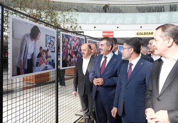 A man speaking at a podium with a backdrop displaying "Eğitimden Bir Kare Fotoğraf Sergisi" and dates 6-12 EYL 2023. Multiple people in formal attire cutting a red ribbon in a spacious indoor area with trees and a glass ceiling. Photographs on display behind a metal fence, including images of children and damaged buildings. Text on banners includes "Millî Eğitim Bakanlığı" and "Gazze".