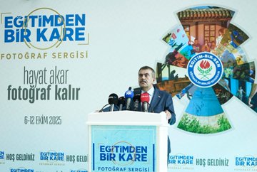 A man in a suit stands at a podium with multiple microphones, including red and black ones, speaking at an event. Behind him, a large banner displays "Eğitimden Bir Kare Fotoğraf Sergisi" with text reading "Hayat akar fotoğraf kalır" and dates "6-12 Ekim 2025." The banner includes logos and images of people and nature. Another image shows a group of people, including men in suits and a woman in a beige coat, cutting a red ribbon in a spacious indoor area with trees and a glass ceiling.