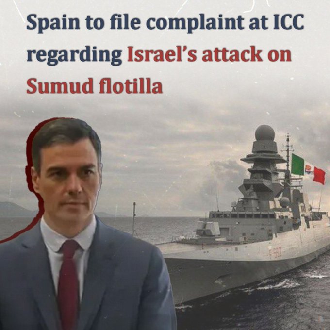 A man with short dark hair wearing a dark suit white shirt and red tie stands seriously looking forward. To his right a large white naval ship with a radar dome and Spanish flag floats on water under a cloudy sky.