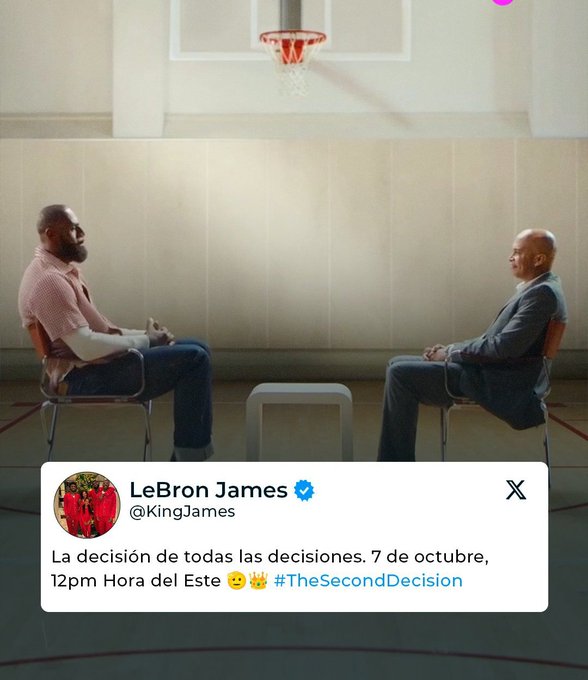 LeBron James se sienta en una silla con una camisa rosa de manga corta y jeans, frente a otro hombre con traje sentado frente a una pequeña mesa en un gimnasio con un aro de baloncesto en el fondo. LeBron James tiene una expresión seria y está gesticulando con la mano. El otro hombre parece estar escuchando atentamente. Una imagen de perfil circular de LeBron James con una camiseta roja se superpone en la esquina. La superposición de texto dice La decisión de todas las decisiones 7 de octubre, 12 pm hora del Este con emojis de baloncesto y corona, y hashtags TheDecision2.
