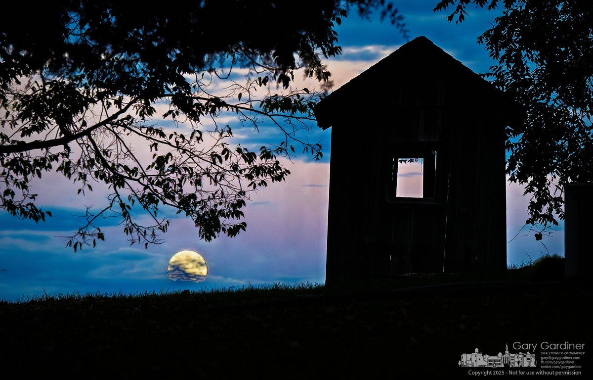 The Harvest Moon rises through low clouds behind the silhouette of a weathered shed near the historic Sharp House on Africa Road.  My Final Photo for October 6, 2025.  1l.ink/FSZCLVV