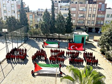 First image shows a school courtyard with students in uniforms standing in groups holding large Palestinian and Turkish flags, surrounded by buildings, trees, and a basketball hoop. Second image depicts students sitting on the ground forming the word FİLİSTİN with their bodies in the courtyard amid trees and structures. Third image captures students seated forming the word GAZZE on the paved school yard with a Turkish flag on a pole nearby and vehicles in the background. Fourth image features a school building with a dome, trees, and students in red and blue uniforms gathered in the courtyard under sunny skies.