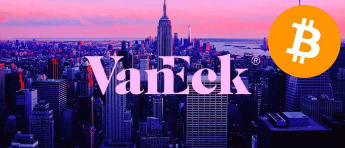 New York City skyline at sunset with the Empire State Building visible in the background over a body of water surrounded by skyscrapers. Prominent pink VanEck logo overlaid multiple times across the image. Orange Bitcoin symbol positioned near the right side next to another VanEck logo.