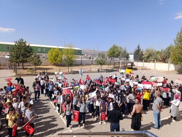 First image shows group of schoolchildren in uniforms standing on steps of yellow building with Golkent Okulu sign, holding white papers or drawings, adults nearby. Second image depicts young girl in pink dress smiling while holding Turkish flag, wearing paper hat, surrounded by children with Palestinian flags. Third image features yellow banner reading Her yer yer Gazze her yer direnis held by man in yellow hoodie, people with Palestinian and Turkish flags in background under blue sky. Fourth image captures large group of students and adults in school yard waving Turkish and Palestinian flags, some holding yellow banners, green building and trees visible.