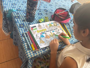 First image shows the front of a school building with a blue sign reading CUMHURIYET ILKOKULU and the Turkish flag emblem, children in colorful clothing standing on steps holding and waving Palestinian and Turkish flags. Second image depicts children on a sunny outdoor playground running and playing with Palestinian flags, some barefoot, against a background of school buildings and trees. Third image features a girl coloring a detailed drawing of Palestinian map, Dome of the Rock, ships, tents, and the number 68 on a checkered table with crayons, pencils, a water bottle, and toys nearby. Fourth image shows another girl at a table cutting or coloring a similar artwork with Palestinian symbols, ships, a girl in headscarf, flags, and landmarks on a blue mat with school bags and supplies around.
