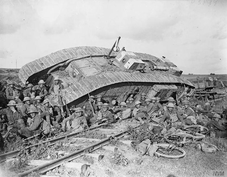 Battle of Cambrai. Men of the 20th Battalion, Manchester Regiment (25th Division) resting by a tank (serial number 9891), disabled by side-slipping down a railway embankment. Near Premont, 8 October 1918.