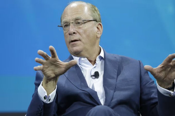 First image shows an older man with glasses wearing a blue suit white shirt and microphone speaking animatedly with hands gesturing on a blue background stage setting. Second image displays a white Bitcoin symbol centered on a solid orange background.