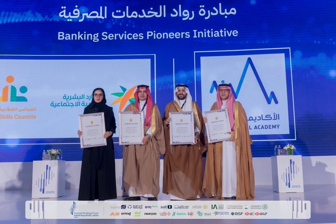 Four individuals in traditional Saudi attire including abayas and thobes stand on a stage holding certificates during an award ceremony. A woman in black abaya holds a certificate on the left, followed by three men in beige thobes each holding certificates. The backdrop features blue and orange banners with Arabic text for Banking Services Pioneers Initiative and Skills Council Financial Academy. Logos of partners like HSBC and SAB are visible at the bottom. Flowers and a podium are present on stage.
