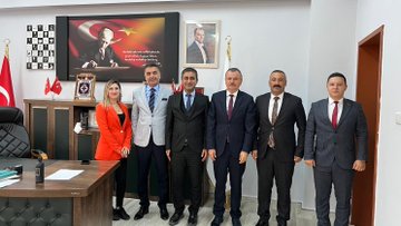 First image shows three men in suits standing in an office with Turkish flags, a framed portrait of Mustafa Kemal Atatürk on the wall, a large screen displaying the Turkish flag, bookshelves, and a wooden desk; one man holds a plaque with the Turkish flag emblem. Second image depicts six people including a woman in an orange top and men in suits posing in front of a large screen with the Turkish flag, a portrait of Atatürk, office chairs, and a door; flags and a framed emblem are visible on shelves. Third image features seven men in suits standing on steps in front of a government building entrance with a sign reading Çukurca Kaymakamlığı, Turkish flags on poles, and architectural elements like columns and windows.