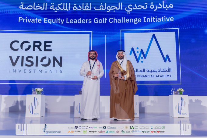 Two men in traditional Saudi attire stand on a stage holding a trophy during an award ceremony. One wears a white thobe and red-checkered shemagh, the other a brown thobe and white ghutra. Blue banners display Private Equity Leaders Golf Challenge Initiative and Core Vision Investments logos. Flowers and additional branding from sponsors like SABIC and HSBC are visible in the background.