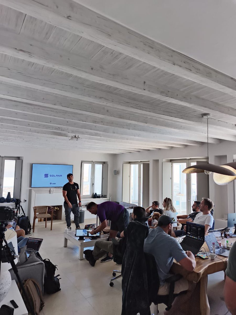 Attendees at Island DAO Mykonos event engaged in a presentation on DAO incorporation with Solana logo displayed on screen