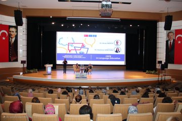 İlk görüntüde büyük bir ekran Plurilingualism involves the ability to use multiple languages veya dillerini kullanma yeteneğini içeren plurilingualism başlığı altında sunum gösteriyor ve iki konuşmacı sahne önünde duruyor. İkinci görüntüde bir konferans salonu kalabalık izleyici koltukları Türk bayrakları ve sahnede moderatör ile panelistler Yabancı Dil Eğitimi in CEFR başlığı altında tartışma yapıyor. Üçüncü görüntüde Dr Nihat ve Dr Nazlı Görgöz isimleri yazılı grup fotoğrafı çeşitli katılımcılar sahne önünde poz veriyor renkli grafik unsurlarla süslenmiş arka plan.