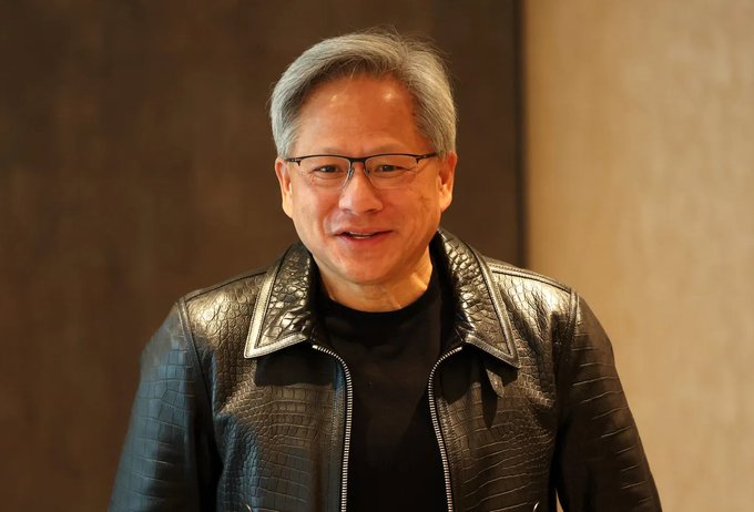 First image shows Jensen Huang, an older Asian man with gray hair and glasses, smiling slightly while wearing a black leather jacket over a black shirt, standing indoors against a wooden wall. Second image depicts Elon Musk, a man with short brown hair, looking serious in a black suit, white shirt, and black tie, seated in a stadium with a blurred crowd and American flags in the background.