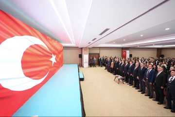 First image shows a large Turkish flag backdrop in a conference hall with rows of formally dressed men standing attentively on a blue stage area. Second image depicts a man in a suit speaking at a podium with a banner reading Ögrenme Güclüü Etkinlik Seti Tanim Toplantisi and the date 5 Ekim 2023 behind him, audience seated in front. Third image features a group of adults and children in formal attire holding musical instruments like flutes and clarinets, standing in front of a Turkish emblem on a wall. Fourth image displays two colorful boxed sets of educational materials labeled ÖGES for learning difficulty awareness series, with illustrated children and books on a table.