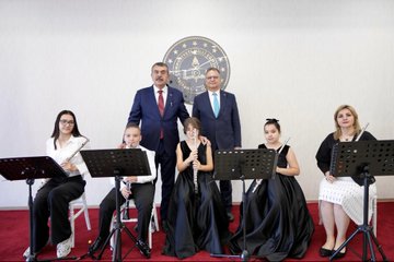 First image shows a large Turkish flag backdrop in a conference hall with rows of formally dressed men standing attentively on a blue stage area. Second image depicts a man in a suit speaking at a podium with a banner reading Ögrenme Güclüü Etkinlik Seti Tanim Toplantisi and the date 5 Ekim 2023 behind him, audience seated in front. Third image features a group of adults and children in formal attire holding musical instruments like flutes and clarinets, standing in front of a Turkish emblem on a wall. Fourth image displays two colorful boxed sets of educational materials labeled ÖGES for learning difficulty awareness series, with illustrated children and books on a table.