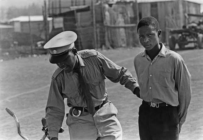 HistorySAZAR's tweet photo. A student who said he was going to fetch his textbook is pulled in. To prove he was still in school he showed his fountain pen and ink-stained fingers. But that was not enough; in long pants he looked older than sixteen, c 1960s. Photographer: Ernest Cole (1940-1990) https://t.co/cgA95iyiCJ