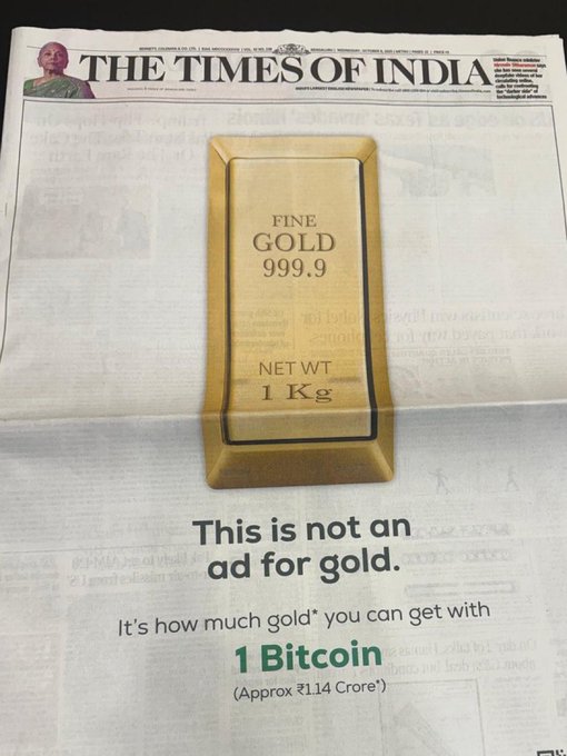 A newspaper front page from the Times of India features a prominent advertisement with an image of a gold bar labeled Fine Gold 999.9 net weight 1 Kg. The ad text states This is not an ad for gold. It is how much Bitcoin you can get with 1 Kg gold approx 71 lakh rupees. The layout includes the newspapers masthead and typical front-page elements.