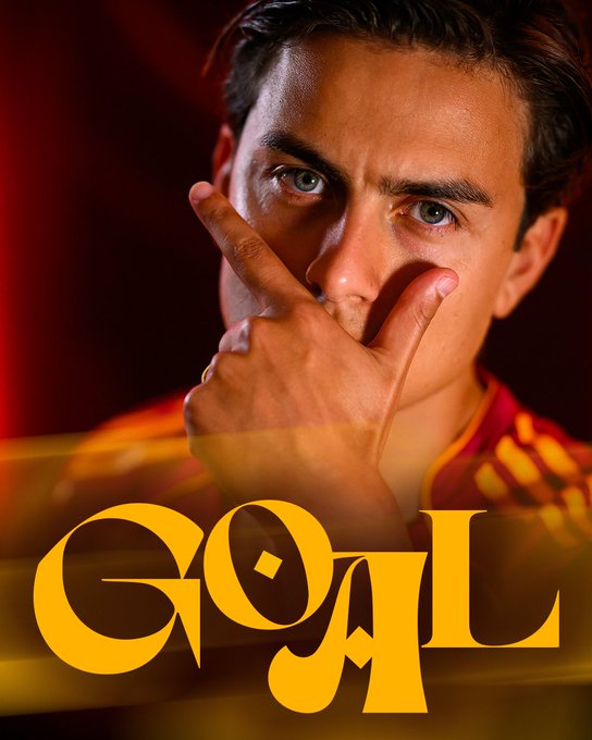 A young man with short dark hair and green eyes wearing an orange and yellow striped soccer jersey poses with his right hand making a finger gun gesture near his mouth while looking directly at the viewer against a red background. Large stylized yellow text reading GOAL is overlaid at the bottom of the image.