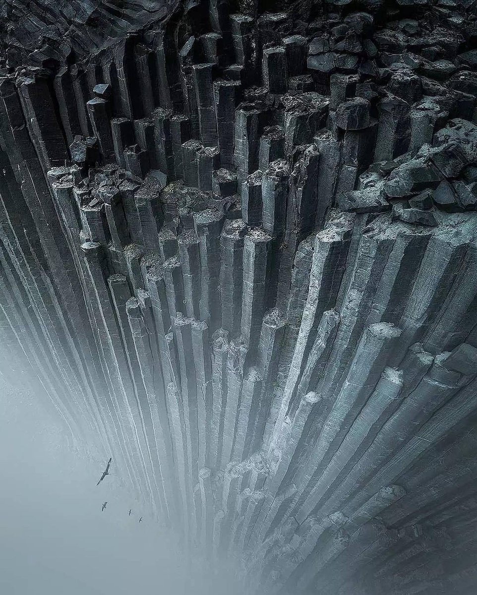 Massive basalt rock columns soaring through the fog of Iceland.