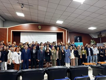 First image shows a promotional graphic with the Milli Egitim Akademisi logo and text in Turkish about ongoing trainer training courses for psychological counselors and guidance teachers focusing on well-being and peer bullying, including a raised hand and group setting illustration. Second image depicts a large group of diverse professionals including men and women in formal attire standing together on a stage in a conference room with wooden paneling, Turkish flags, and a portrait on the wall. Third image is a collage of four scenes: participants seated around tables in a classroom with notebooks and a projector, another group discussion with balloons, and educators interacting in training sessions. Fourth image is another collage showing similar classroom activities with participants engaged in discussions around tables, using projectors and whiteboards in educational environments.