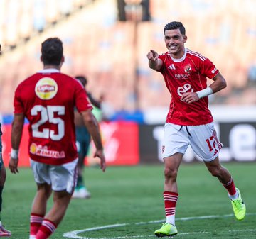 First image shows a player in red Al Ahly jersey number 17 pointing and smiling on a stadium field with another player in green jersey behind. Second image captures two players in red jerseys facing each other smiling broadly during celebration with sponsor logos visible. Third image depicts a player in red jersey number 14 running and pointing on the field with another player in red jersey number 25 nearby.