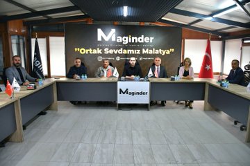 First image shows a group of eight people standing together in a formal indoor setting with a large banner reading MAGİNDER and Malatya behind them, including men and women in suits and casual attire, Turkish flags on poles. Second image depicts two men seated at a table in discussion, one in a black shirt gesturing, the other in a suit with a red tie, water bottles and documents on the table, banner with www.magland.org and Facebook logo. Third image features three people at a table, a man in black shirt, an older man in suit with purple tie, and a woman in pink blouse, with Turkish and white flags, water bottles, banner reading Vakfımız Malatya. Fourth image shows seven people seated around a conference table with water glasses, banner reading MAGİNDER and Ortak Sevdamız Malatya, Turkish flags, participants in formal clothing including suits and dresses.