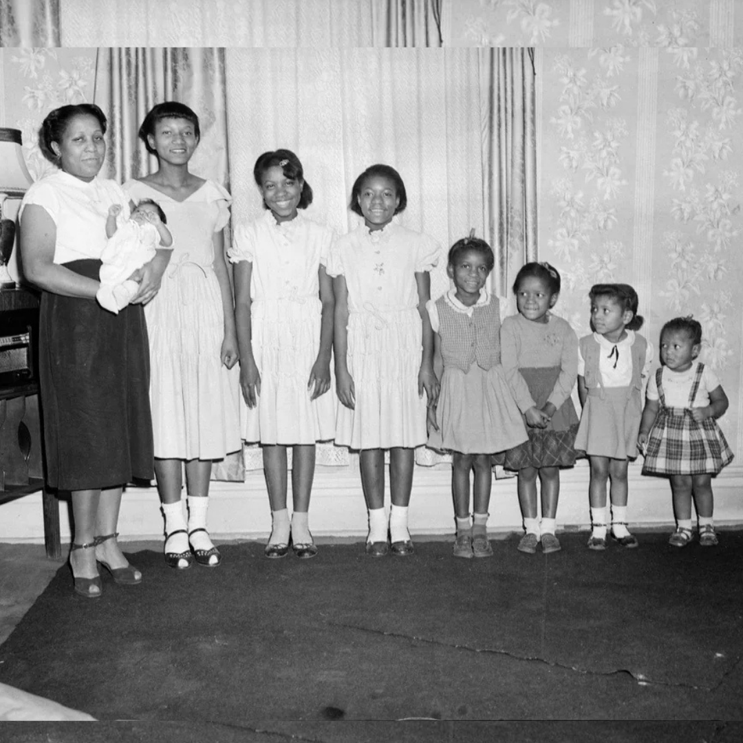 Mother smiles as she poses with her 8 children, circa 1950s