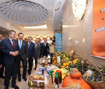 First image shows two suited men, one with glasses and the other with a mustache, sitting at a table signing documents under a blue banner reading Tarım Sektörüne Yönelik Teknik Eğitim İş Birliği Protokolü with Turkish flags and TOBB emblem dated 23 Eki 2025. Second image depicts several suited officials standing in an elegant room with ornate ceiling and chandelier, near a table displaying agricultural products including jars, bottles, fruits like bananas and pumpkins, vegetables, and a woven basket, with a orange banner in the background. Third image captures a large group of about 20 suited men standing in a grand room with chandelier and curtains, some holding documents at small tables with water bottles. Fourth image features a wide group of around 30 suited men standing on a wooden floor in front of a blue banner with Turkish crescent emblem, posed formally in rows.