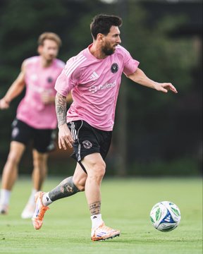 First image shows Lionel Messi sitting relaxed in a striped beach chair on sand, wearing a pink Inter Miami jersey with number 10, tattoos visible on arms and legs, holding a document labeled Contract 2023 in one hand and a drink in the other, with feet in flip-flops, a large soccer ball nearby, palm trees and a yellow building with Messi 10 sign in the background under a blue sky. Second image depicts Lionel Messi on a green field during training, dressed in pink Inter Miami training shirt and black shorts, tattoos on legs, running with one leg extended kicking a white soccer ball with green and blue patterns, another player in pink gear visible behind him, wearing orange and white sneakers.