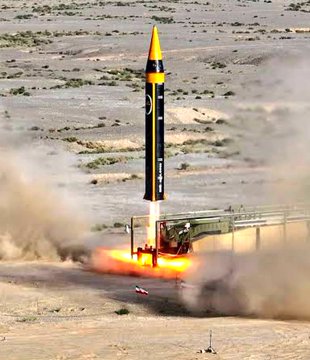 First image shows a soldier wearing camouflage uniform green beret gold-tinted goggles and face covering standing in profile holding a rifle with a yellow conical missile mounted on a launcher behind him in a desert landscape under clear sky. Second image depicts a tall black missile with yellow tip and black stripes launching vertically from a metal platform in sandy desert area with orange flames smoke billowing from base and Iranian flag visible nearby.