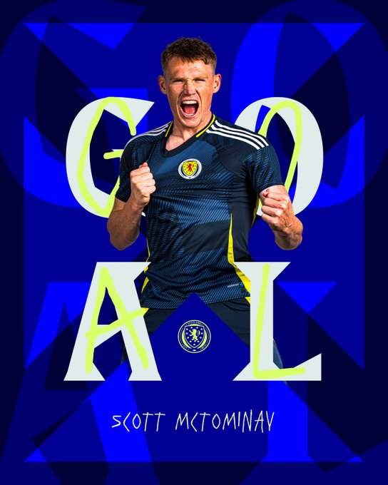 A young man with short brown hair and a determined expression wears a dark blue Scotland national team soccer jersey with yellow accents and the team crest on his chest, standing with arms raised in celebration as if shouting in excitement. Large bold white letters spelling GOAL overlay the image in a dynamic font. The background is a solid blue with subtle patterns, and the text Scott McTominay appears at the bottom in white stylized lettering.