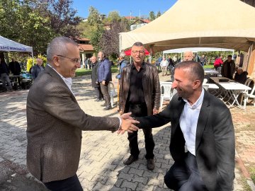 First image shows two men in suits shaking hands outdoors near beige tents with Turkish flags, surrounded by other suited men and autumn trees under a clear sky. Second image depicts four men in formal wear including jackets and glasses shaking hands beside a white tent labeled with Turkish text amid yellow foliage and more tents. Third image features eight older men in suits and jackets seated around white tables under a canopy next to stone walls, some holding phones. Fourth image displays groups of people in dark uniforms seated at tables under a white tent with Turkish text, near purple trees and benches in a park-like setting.