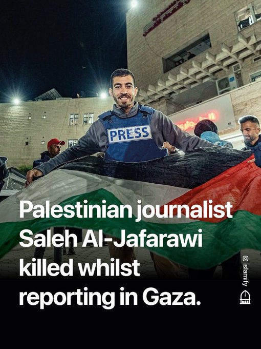 A man wearing a gray hooded sweatshirt and a blue press vest labeled PRESS stands smiling in front of a beige building at night under bright lights, holding a large Palestinian flag with others nearby including men in red caps and vests, with overlaid text stating Palestinian journalist Saleh Al-Jafarawi killed whilst reporting in Gaza.