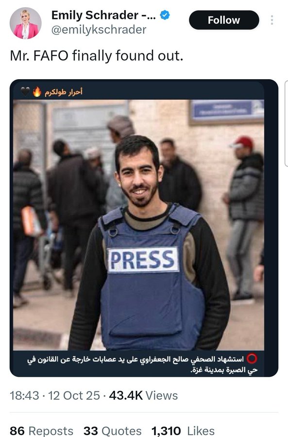 A man with a beard wearing a blue press vest labeled PRESS stands outdoors in front of a beige building, smiling slightly, with other people in casual clothes and hats visible in the background. Arabic text appears overlaid at the bottom. The quoted tweet interface shows Emily Schrader as the author with a profile image of a woman in pink.