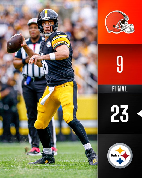 Quarterback Mason Rudolph in black and yellow Pittsburgh Steelers uniform with number 8 throws a football while in motion on a green football field during a game against the Cleveland Browns, with a referee in black and white stripes nearby and stadium crowd in background, overlaid with Cleveland Browns helmet logo, score 9, final indicator, and score 23.