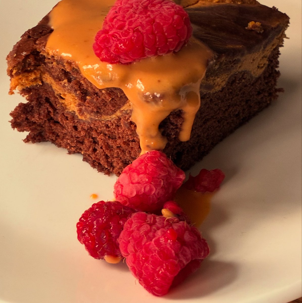 Product photo I shot of chocolate pumpkin cheesecake with a salted caramel sauce and raspberries.