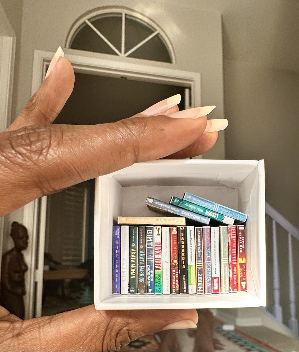 Nnedi's tweet image. A woman in my book-signing line at the Heartland Book Festival gave me these miniature versions of my books. So delightful! 📚I&apos;m going to keep this tiny library on my desk. Nearly every book I&apos;ve written.
