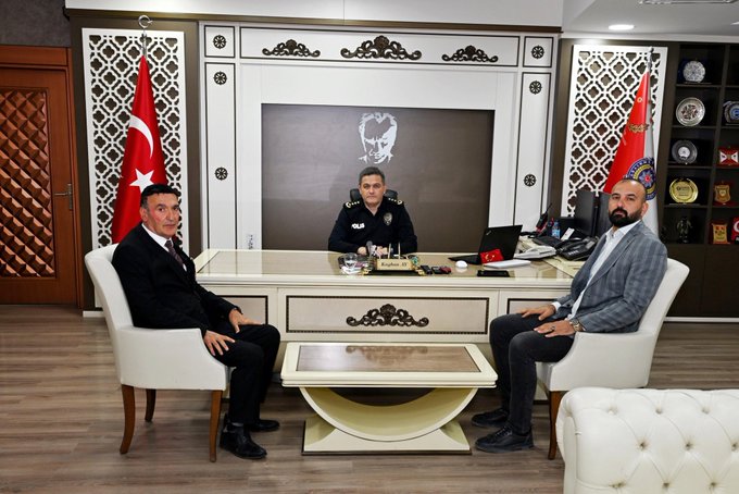 İlk görüntüde üç adam resmi bir ofiste oturuyor bir polis üniformalı adam ortada masa başında iki sivil giyimli adam yanlarda koltuklarda Türk bayrakları duvarlarda asılı dekoratif unsurlar var. İkinci görüntüde üç adam ayakta poz veriyor polis üniformalı adam ortada iki sivil giyimli adam yanlarda Türk bayrağı ve polis amblemi duvarlarda görülüyor masa ve koltuklar ofis ortamında.