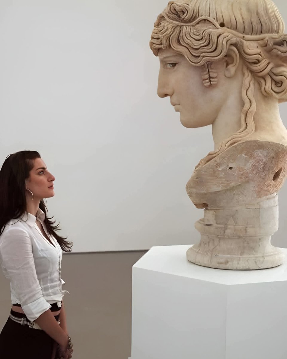 dealbi's tweet image. A Greek woman looks at an ancient Hellenistic sculpture, dating from around 130 AD. The striking resemblance in the proportions and facial features can be seen...#LouvreMuseum