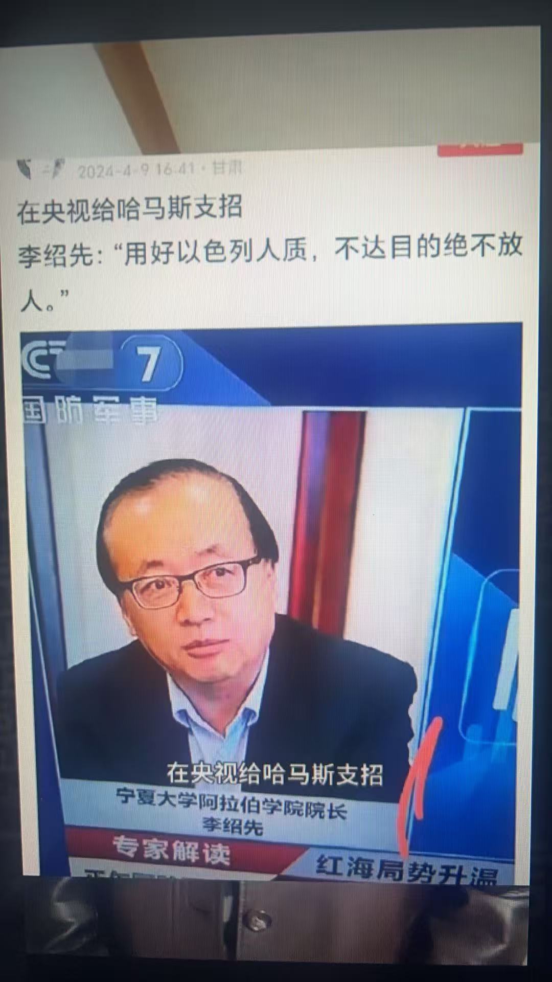 央视新闻广播截图，李绍先是一名戴眼镜、身穿西装的中年男子，在演播室环境中对着麦克风讲话，中文文字叠加讨论哈马斯对以色列人质的战略和相关地缘政治话题。