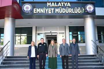 First image shows two individuals standing formally in a room adorned with Turkish flags on either side and a portrait on the wall behind them. A woman in a green dress and gray jacket stands next to a man in a navy police uniform with badges. They are positioned in front of a podium with microphones and additional flags including the Turkish and another red-white flag. The setting appears official with wooden paneling and ceiling lights. Second image depicts a group of people walking down outdoor steps near parked cars under a clear sky. Several men in suits and police uniforms escort a woman in a green dress and another in gray attire. Police officers in navy uniforms with hats and belts are visible guiding the group. Cars including white and silver vehicles are parked nearby with yellow barriers. Third image features five people standing on steps in front of a building entrance marked with Malatya İl Emniyet Müdürlüğü sign and emblems. A woman in blue jacket white shirt and jeans stands beside a man in police uniform then a woman in green dress gray jacket followed by two men in gray suits. The building has glass doors columns and red accents with Turkish flags.