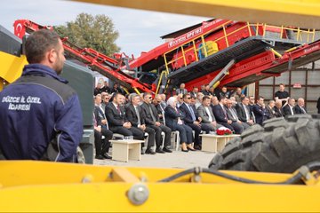 First image shows a group of officials in suits cutting a red ribbon on a blue stage with Turkish flags and large banners of President Recep Tayyip Erdogan, under a metal frame structure. Second image depicts officials standing beside red Boratas branded construction machinery including a crusher and excavator in an industrial yard. Third image captures officials seated on chairs near yellow and red heavy machinery like a loader and crusher, with some wearing work vests. Fourth image features a large banner of President Recep Tayyip Erdogan and groups of officials near yellow Komatsu excavators, red fire trucks, and other construction equipment in an open yard with buildings in the background.