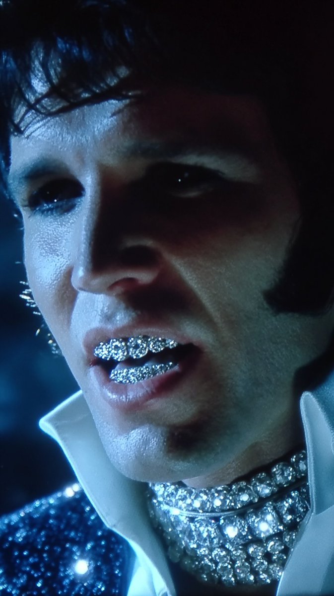 swayducky's tweet image. Midjourney PROMPT:

&quot;VHS screengrab of close up: peter weller as young elvis presley, with extremely white teeth covered in diamond grillz, with black hair, with silver rhinestone necklace, in an all glitter blue tuxedo at night time in space, star trek movie by ridley scott,…