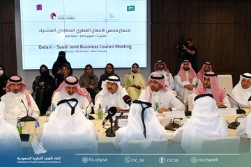 First image displays a large group of men and women in traditional white thobes and abayas standing in a row inside a modern conference room with wooden walls and blue accents posing formally for a group photo with the Federation of Saudi Chambers logo at the bottom. Second image shows a man in white thobe and red and white checkered headscarf with mustache seated at a podium speaking into a microphone during a meeting with a nameplate and logos visible. Third image depicts participants including men in thobes and women in abayas seated around a conference table in a room with a screen displaying the Qatar-Saudi Joint Business Council meeting title in Arabic and flags of both countries with a photographer in the background.
