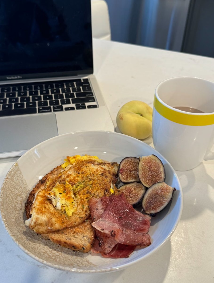 XEmmelie's tweet photo. Breakfast time, a perfect balance between work and deliciousness! 🍳🥓 Two slices of toast, a fried egg, bacon, sweet figs, and a refreshing peach🍑, paired with a cup of hot tea, is the perfect start to a busy day! 💻☕ Mornings like this are full of energy! 💪 #SimpleDelicious #WorkPartner